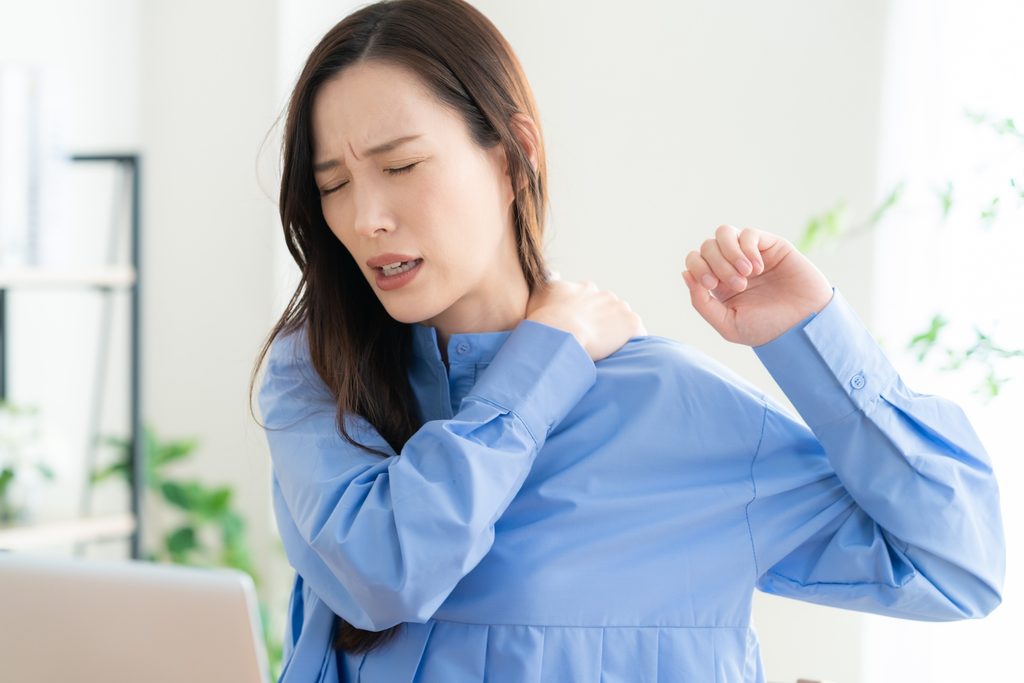 肩を回して肩こりを紛らわせようとしている女性
